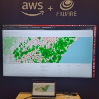 A photo of a desktop computer with a screen of a map with aggregated dots as part of the AWS + FIWARE Garnet Framework stand
