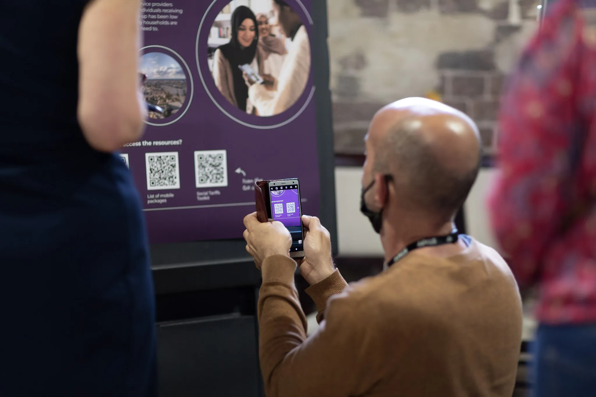 A photo of a man scanning a QR code on one of the exhibition posters.