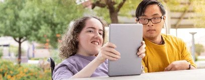 Two individuals with disabilities using an electronic tablet together