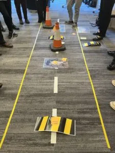 A road on the floor of a room with traffic cones and speed breakers on it