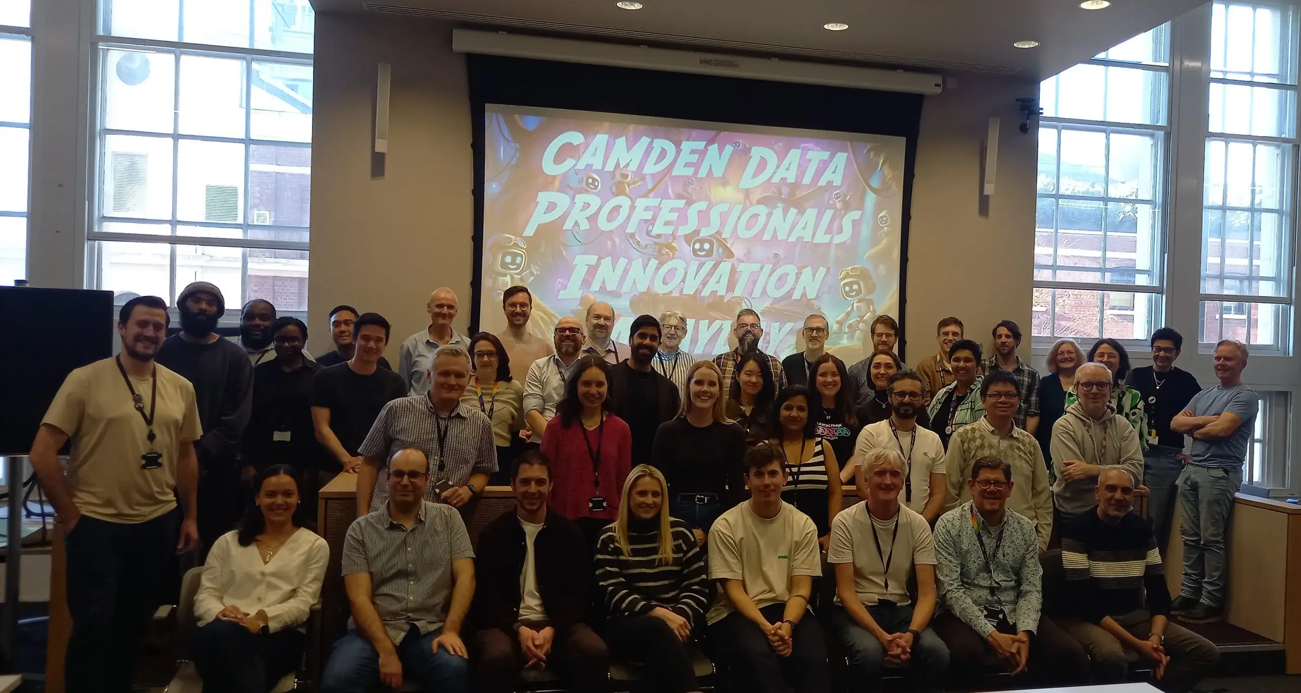 Several individuals standing together for a photo, with a large screen featuring vibrant images in the background.