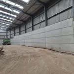 an image of a waste transfer industrial site, a large building with windows on the roof that is cleared with no industrial waste